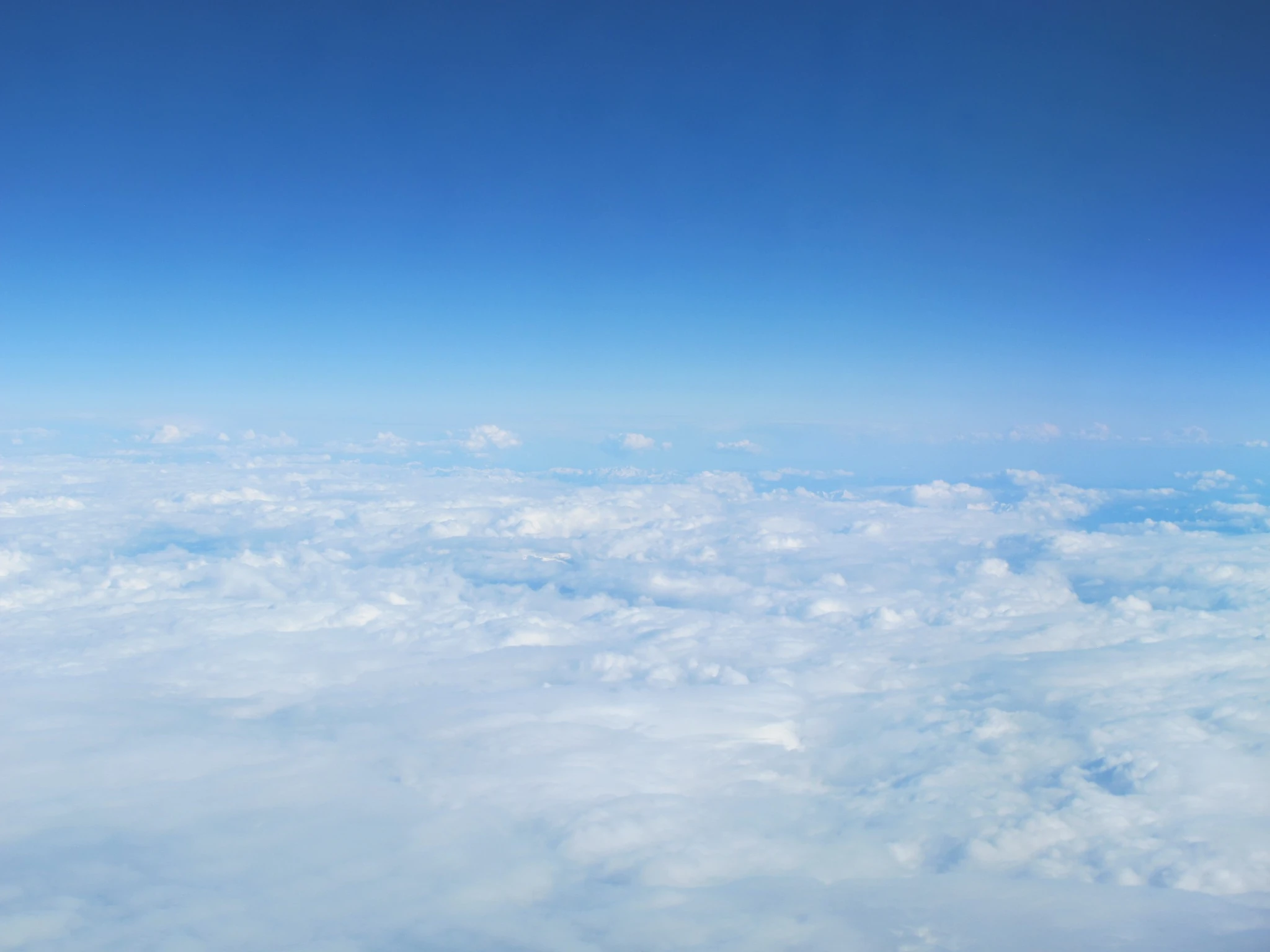 Blue sky above a wide layer of white clouds