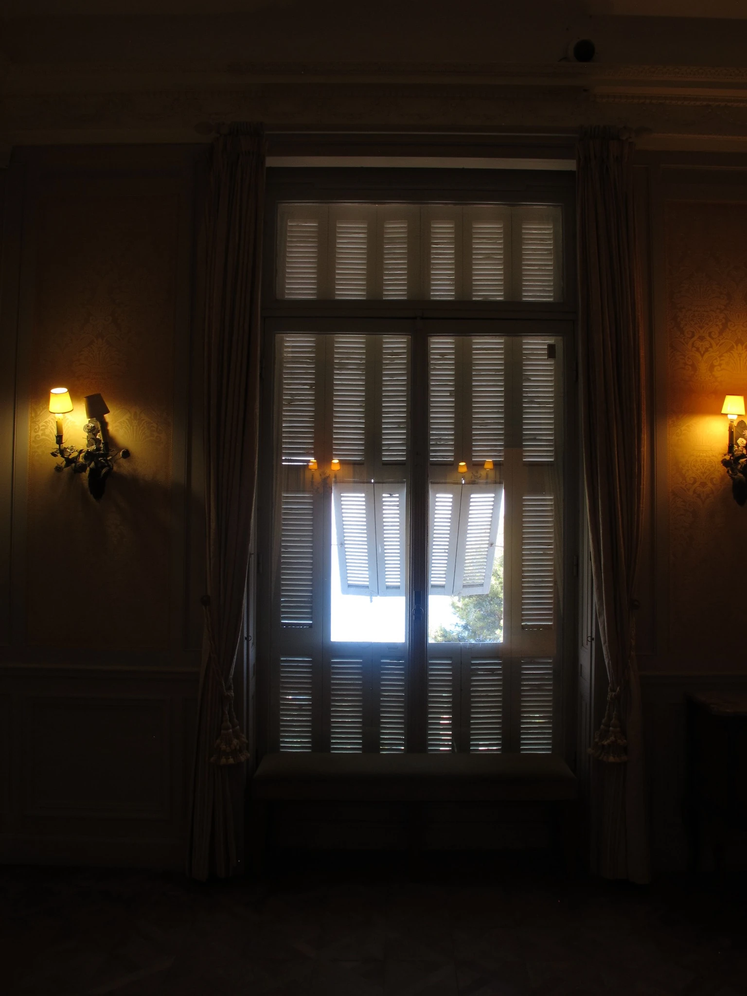 Tall shuttered window in a dark Riviera interior