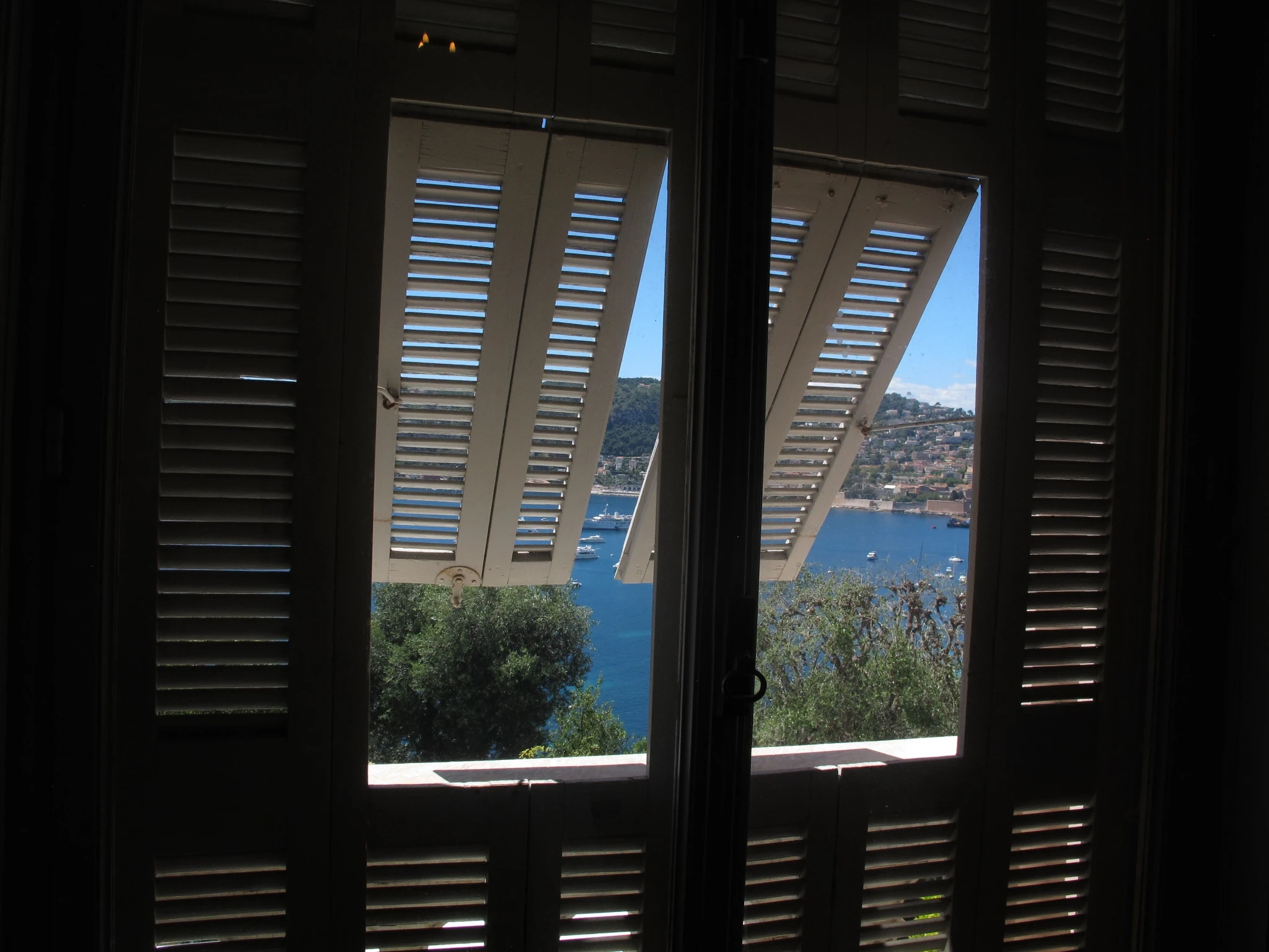 Mediterranean bay seen through open shutters